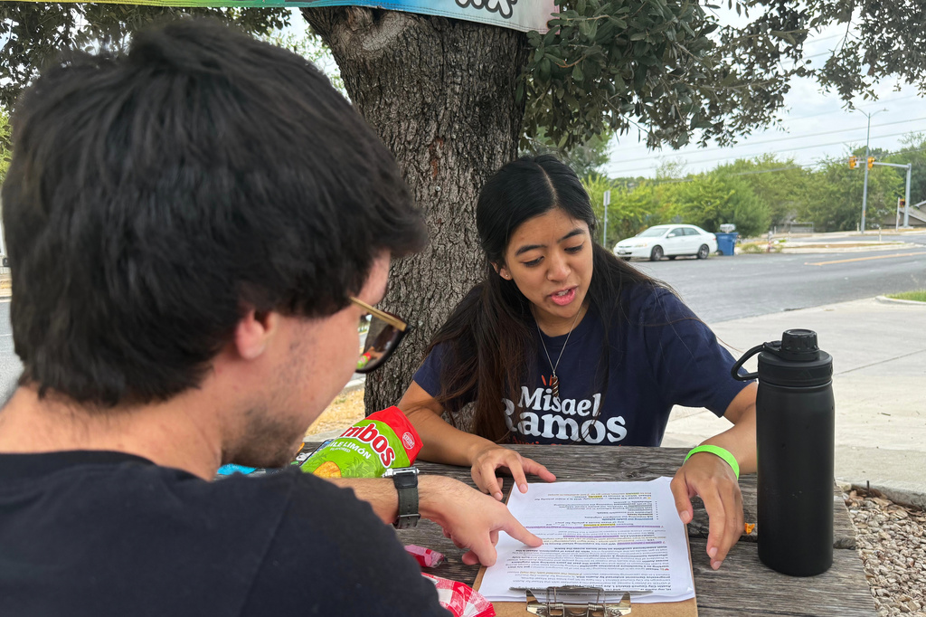 This photo taken with a smartphone shows two members of the Democratic Socialists of America, Mark Ramirez and Clarisse Manuel, during a day of canvassing Saturday, Sept. 26, 2026, in Austin, Texas. (AP Photo/Jesse Bedayn)