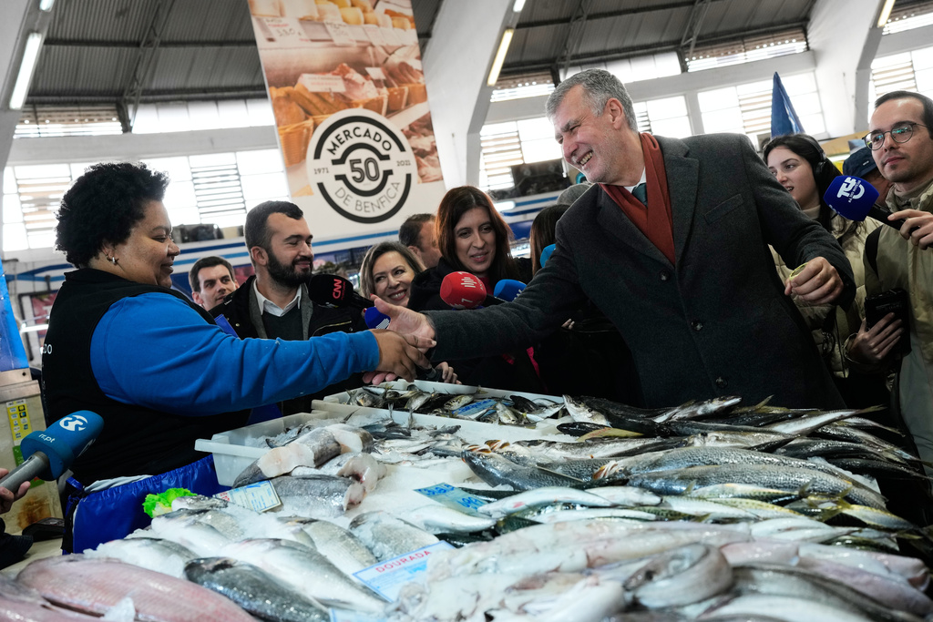 Presidential candidate Henrique Gouveia e Melo, a retired Rear Admiral running as an independent, shakes hands with a fish seller at a market in Lisbon, Friday, Jan. 16, 2026, while campaigning for Sunday's presidential election. (AP Photo/Armando Franca)