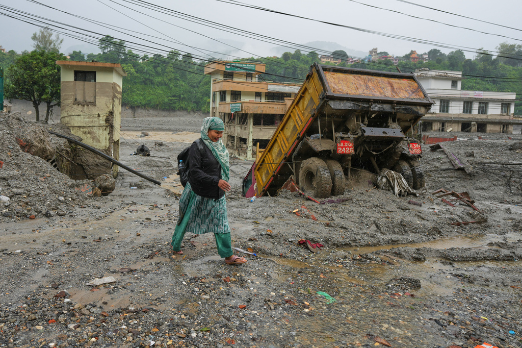 A woman walks through mud and debris left behind by flash flooding in Nepal's Nuwakot district, Saturday, Aug. 29, 2026. (AP Photo/Rajesh Kumar Singh)