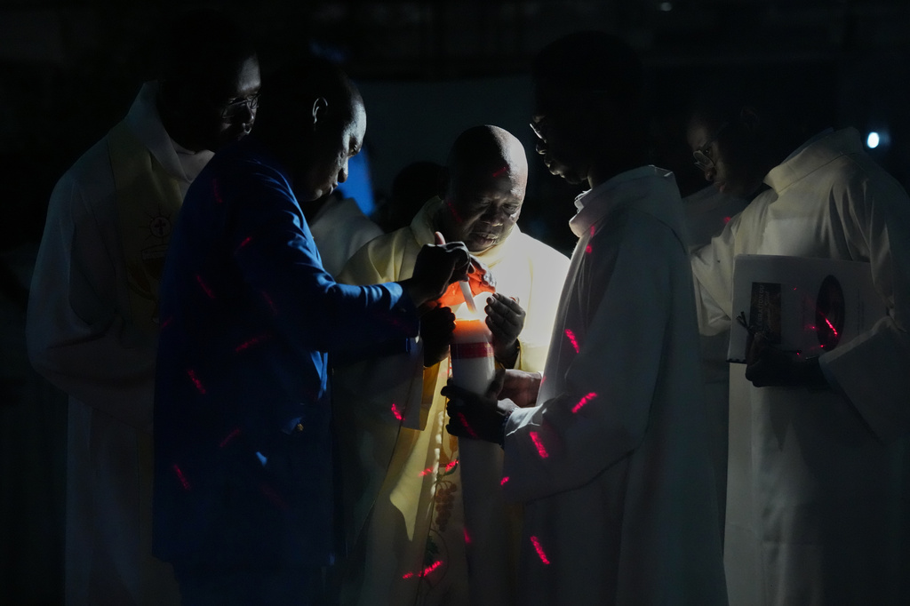 Worshippers light candles at Our Lady of the Angels Church during the Easter Vigil Mass in Dakar, Senegal, Saturday, April 4, 2026. (AP Photo/Misper Apawu)