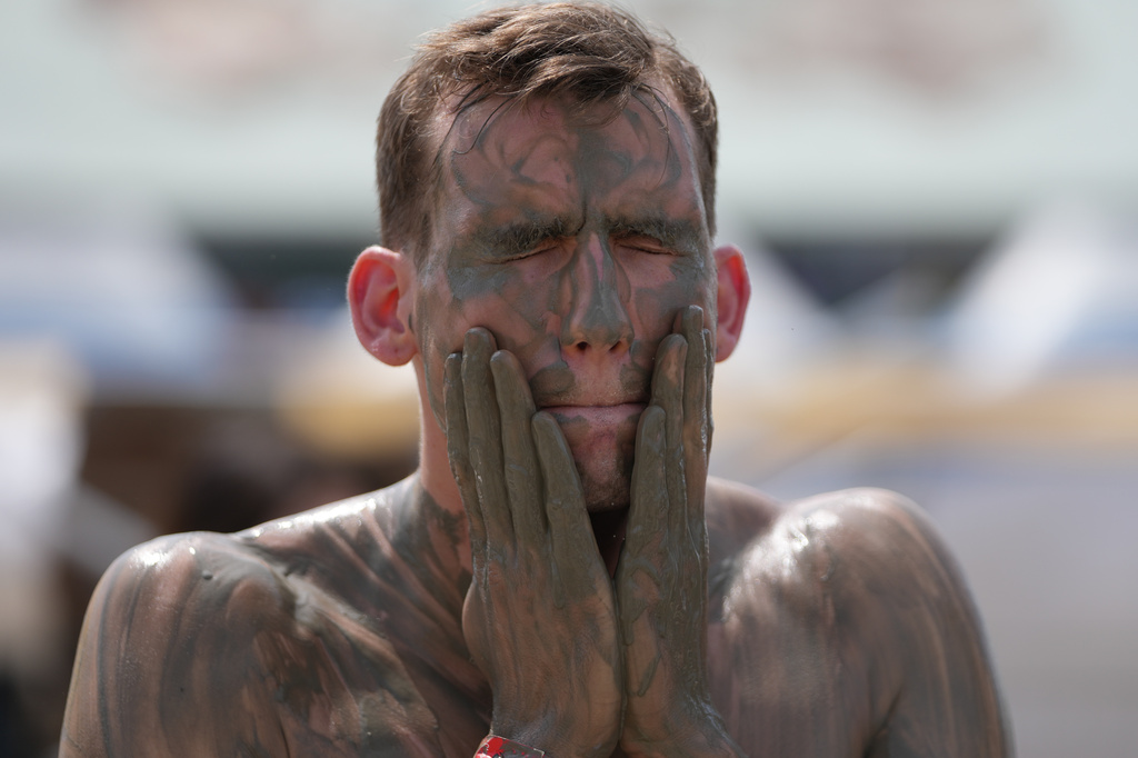 David Gogev of the U.S. paints his face with mud during the Boryeong Mud Festival near a beach in Boryeong, South Korea, Saturday, July 25, 2026. (AP Photo/Lee Jin-man)