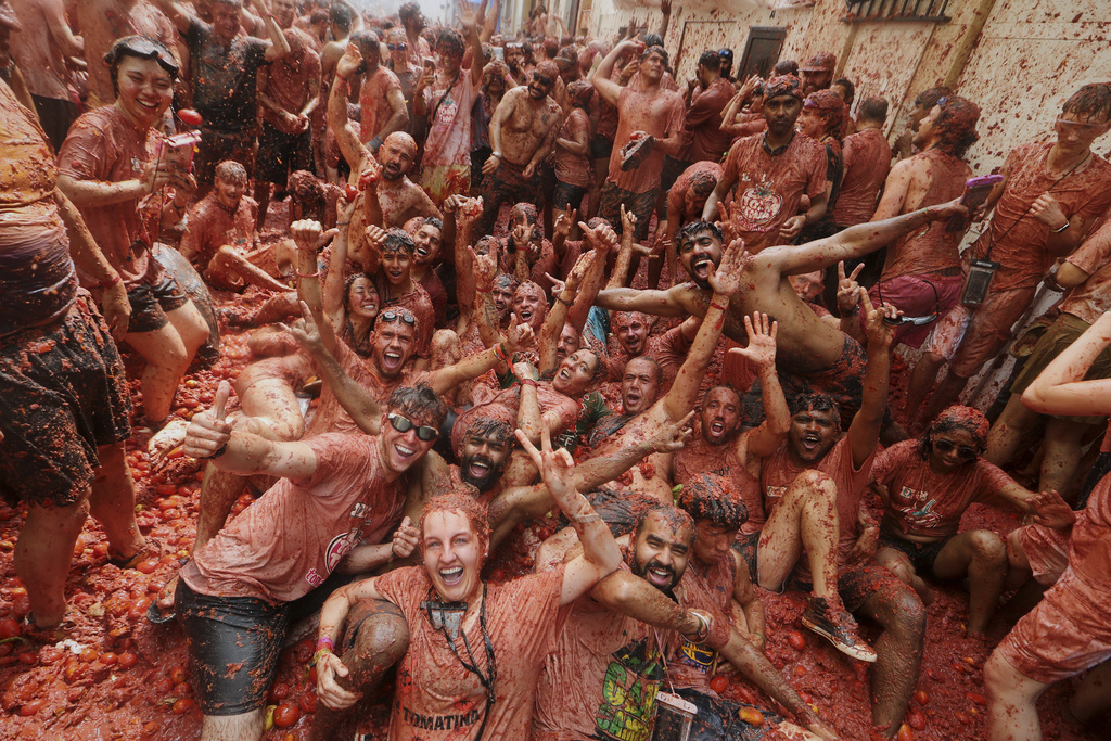 Revelers pose for a photo as they throw tomatoes at each other during the annual "Tomatina" tomato fight fiesta, in the village of Bunol near Valencia, Spain, Wednesday, Aug. 27, 2025. (AP Photo/Alberto Saiz)