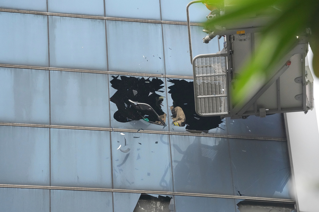 A firefighter breaks glass in an office building that caught fire in Jakarta, Indonesia, Tuesday, Dec. 9, 2025. (AP Photo/Dita Alangkara)