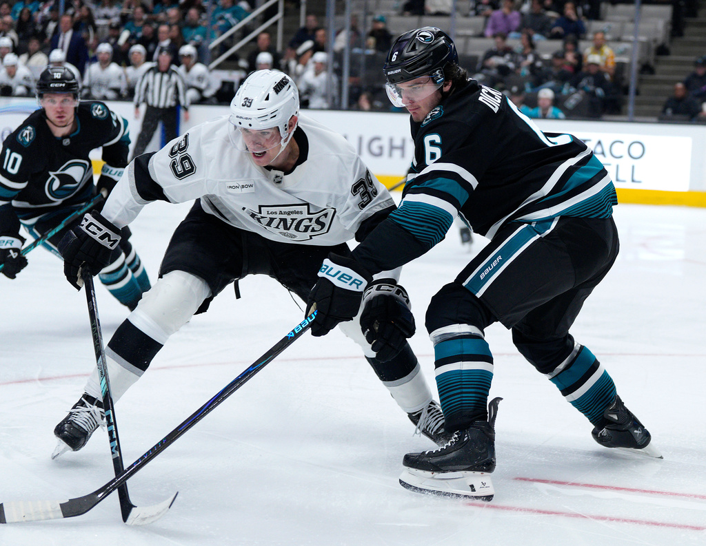 Los Angeles Kings left wing Jeff Malott (39) battles for the puck against San Jose Sharks defenseman Sam Dickinson (6) during the second period of an NHL hockey game in San Jose, Calif., Tuesday, Oct. 28, 2025. (AP Photo/Tony Avelar)