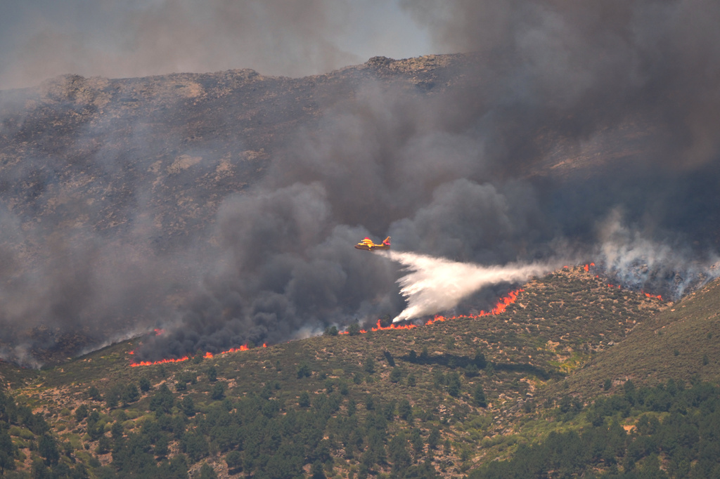 A seaplane drops water onto the fire as a wildfire advances near La Adrada, Ávila province, Spain, Friday, July 24, 2026. (AP Photo/Manu Fernandez)