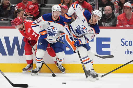 Edmonton Oilers center Connor McDavid, right, moves the puck past Oilers left wing Andrew Mangiapane, center, and Detroit Red Wings center Dylan Larkin, left, during the first period of an NHL hockey game Sunday, Oct. 19, 2025, in Detroit. (AP Photo/Ryan Sun) Edmonton Oilers center Connor McDavid, right, moves the puck past Oilers left wing Andrew Mangiapane, center, and Detroit Red Wings center Dylan Larkin, left, during the first period of an NHL hockey game Sunday, Oct. 19, 2025, in Detroit. (AP Photo/Ryan Sun)