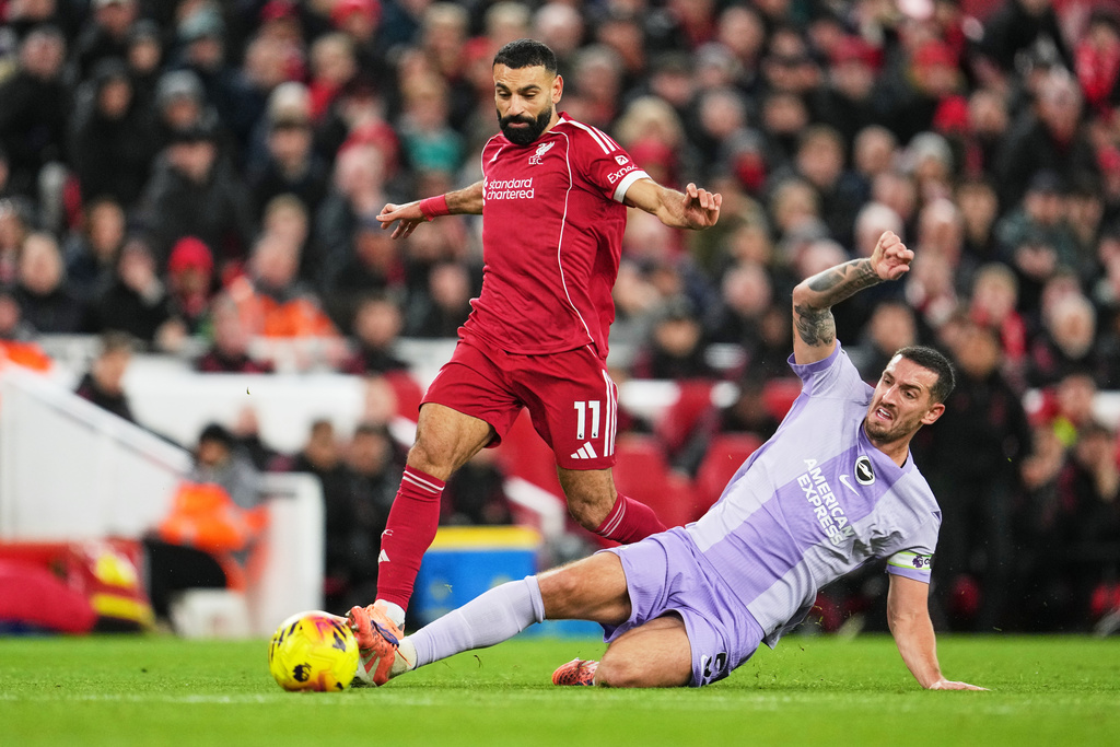 Liverpool's Mohamed Salah, left, challenges for the ball with Brighton's Lewis Dunk during the English Premier League soccer match between Liverpool and Brighton and Hove Albion in Liverpool, England, Saturday, Dec. 13, 2025. (AP Photo/Jon Super)