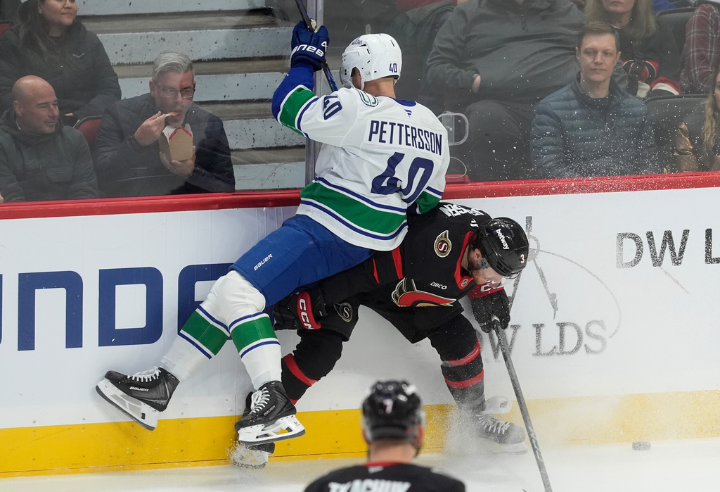 Vancouver Canucks centre Elias Pettersson (40) collides with Ottawa Senators defenseman Nick Jensen (3) along the boards during first period NHL action in Ottawa, Tuesday, Jan. 13, 2026. (Adrian Wyld/The Canadian Press via AP)