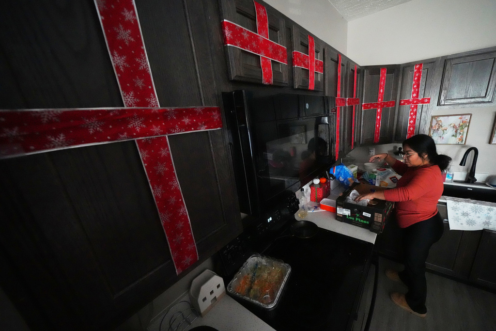 Cristina Osornio unpacks a box of groceries that was delivered to her home by a member of a community group, Nov. 18, 2025, in Rogers, Ark. (AP Photo/Julio Cortez)