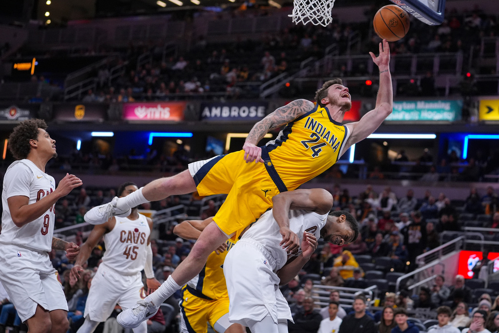 Indiana Pacers guard Garrison Mathews (24) is fouled as he shoots over Cleveland Cavaliers forward De'Andre Hunter (12) during the second half of an NBA basketball game in Indianapolis, Monday, Dec. 1, 2025. (AP Photo/Michael Conroy)