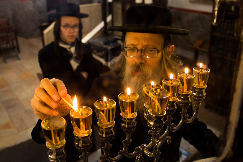 FILE - A Jewish ultra-Orthodox man lights candles during the last day of Jewish holiday of Hanukkah in Jerusalem's Mea Shearim neighborhood, Wednesday, Dec. 4, 2013. (AP Photo/Bernat Armangue, File)
