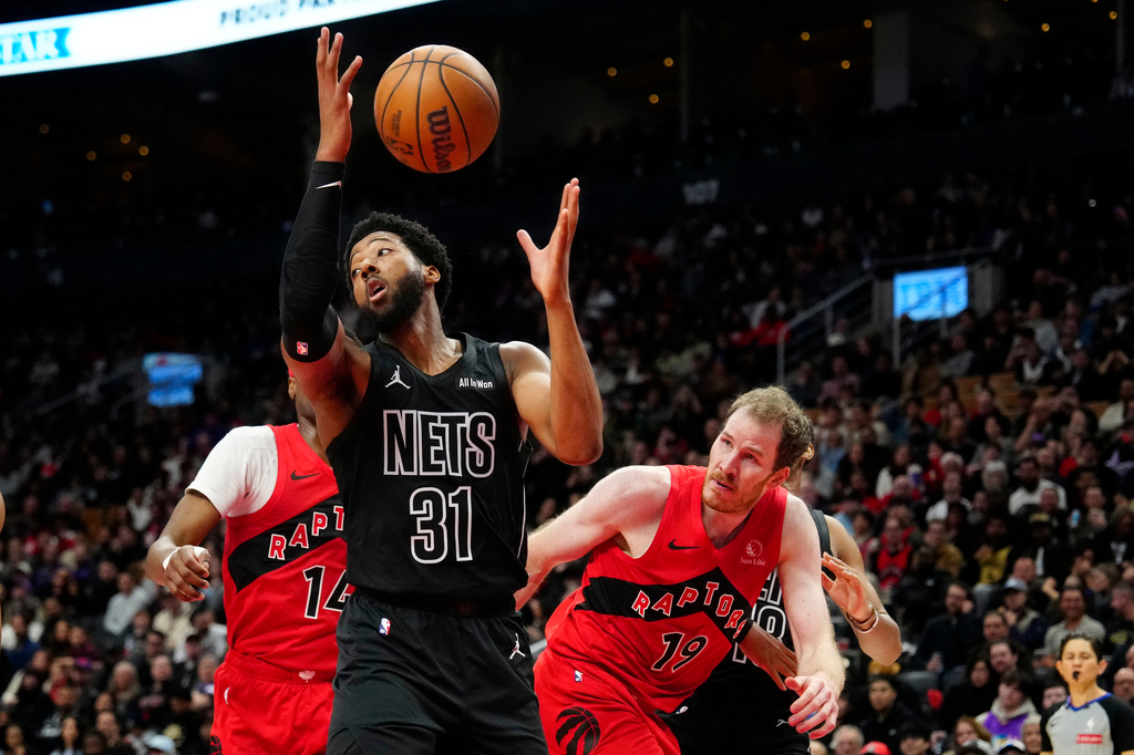 Brooklyn Nets forward Chaney Johnson (31) catches a rebound in front of Toronto Raptors centerJakob Poeltl (19) and Ja'kobe Walter (14) during first-half NBA basketball game action in Toronto, Sunday, April 12, 2026. (Frank Gunn/The Canadian Press via AP
