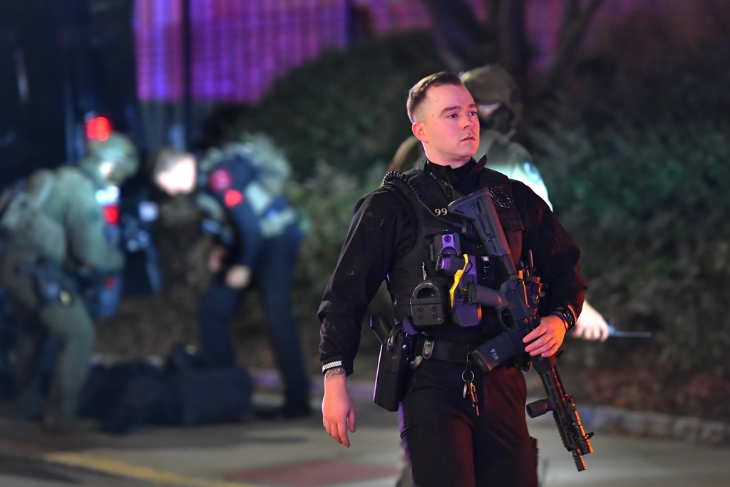 A law enforcement official carries a rifle in a neighborhood near Brown University, Saturday, Dec. 13, 2025, in Providence, R.I. during the investigation of a shooting. (AP Photo/Steven Senne)