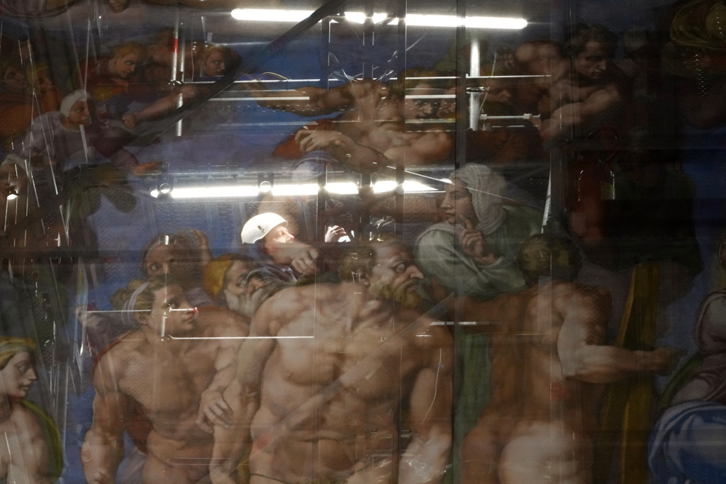 A man walks behind a screen with a replica of “The Last Judgment,” superimposed on it that covers the scaffolding used for its extraordinary maintenance during a presentation for press in the Sistine Chapel at the Vatican, Saturday, Feb. 28, 2026. (AP Photo/Alessandra Tarantino)