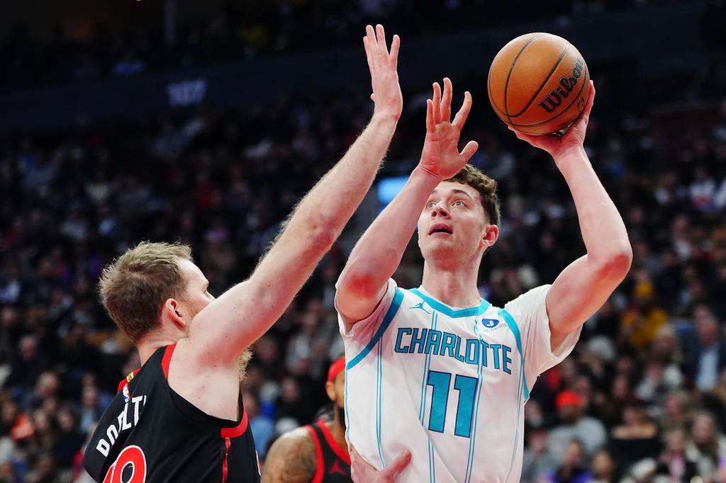 Charlotte Hornets' Ryan Kalkbrenner (11) shoots over Toronto Raptors' Jakob Poeltl (19) during first half NBA basketball action in Toronto on Friday, Dec. 5, 2025. (Frank Gunn/The Canadian Press via AP)