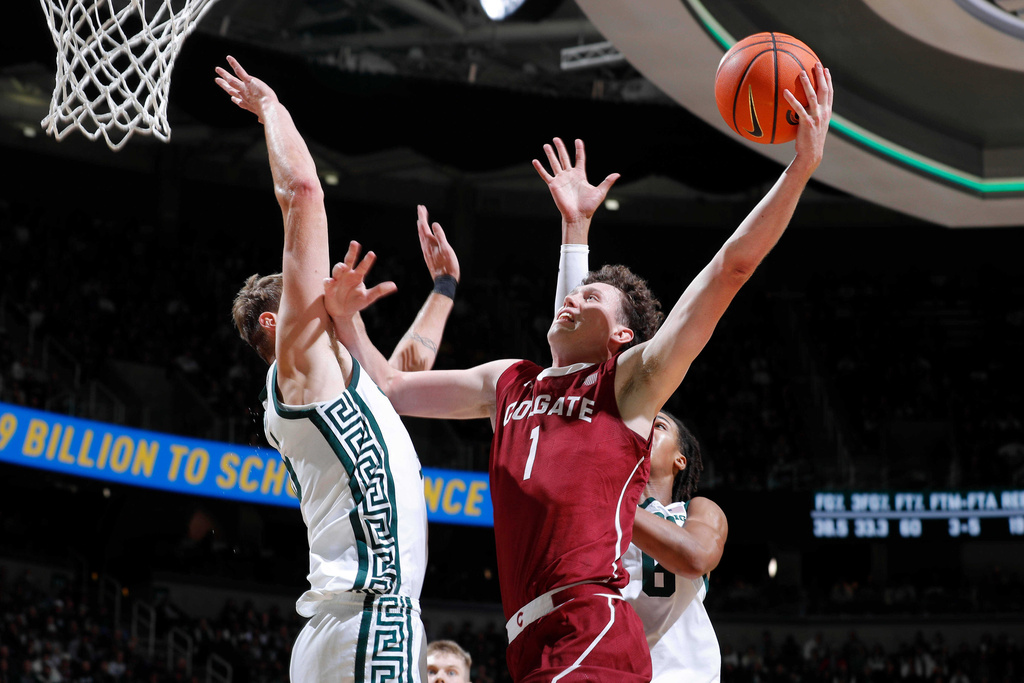 Colgate guard Brady Cummins (1) shoots against Michigan State center Carson Cooper, left, and forward Jordan Scott, right, during the first half of an NCAA college basketball game, Monday, Nov. 3, 2025, in East Lansing, Mich. (AP Photo/Al Goldis)