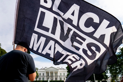 FILE - A man carries a Black Lives Matter flag in Lafayette Square outside the White House on the fourth night of the Republican National Convention, Aug. 27, 2020, in Washington. (AP Photo/Andrew Harnik, File) FILE - A man carries a Black Lives Matter flag in Lafayette Square outside the White House on the fourth night of the Republican National Convention, Aug. 27, 2020, in Washington. (AP Photo/Andrew Harnik, File)