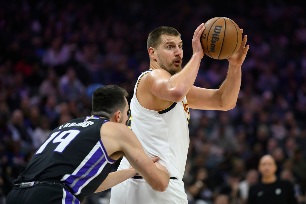 Denver Nuggets center Nikola Jokić, right, prepares to pass the ball past Sacramento Kings forward/center Drew Eubanks (19) during the first half of an NBA basketball game in Sacramento, Calif., Tuesday, Nov. 11, 2025. (AP Photo/Randall Benton)
