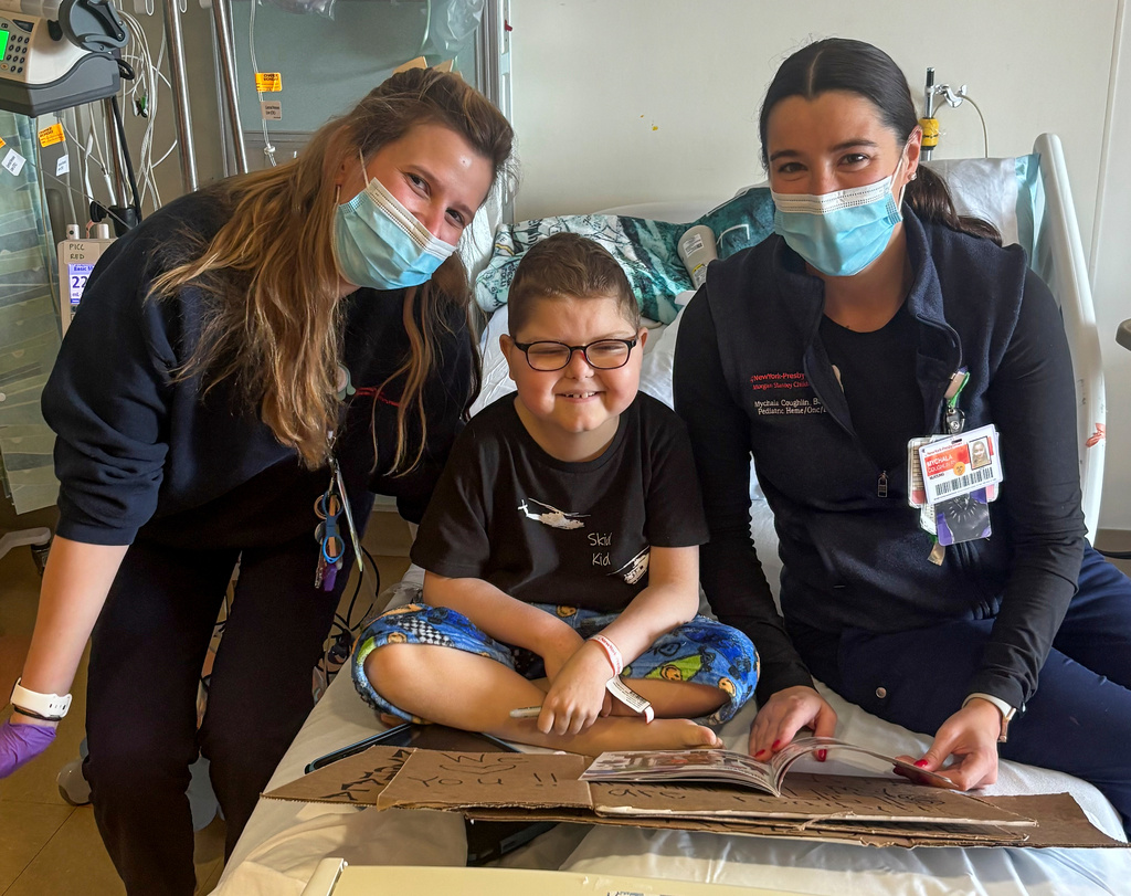 Logan Coyle, 9 years old, center, poses for a photo with two of his primary nurses, Morgan Bieler, left, and Mychala Coughlin in his room at NewYork Presbyterian Hospital, Nov. 5, 2025, in New York. (Jeffrey Coyle via AP)