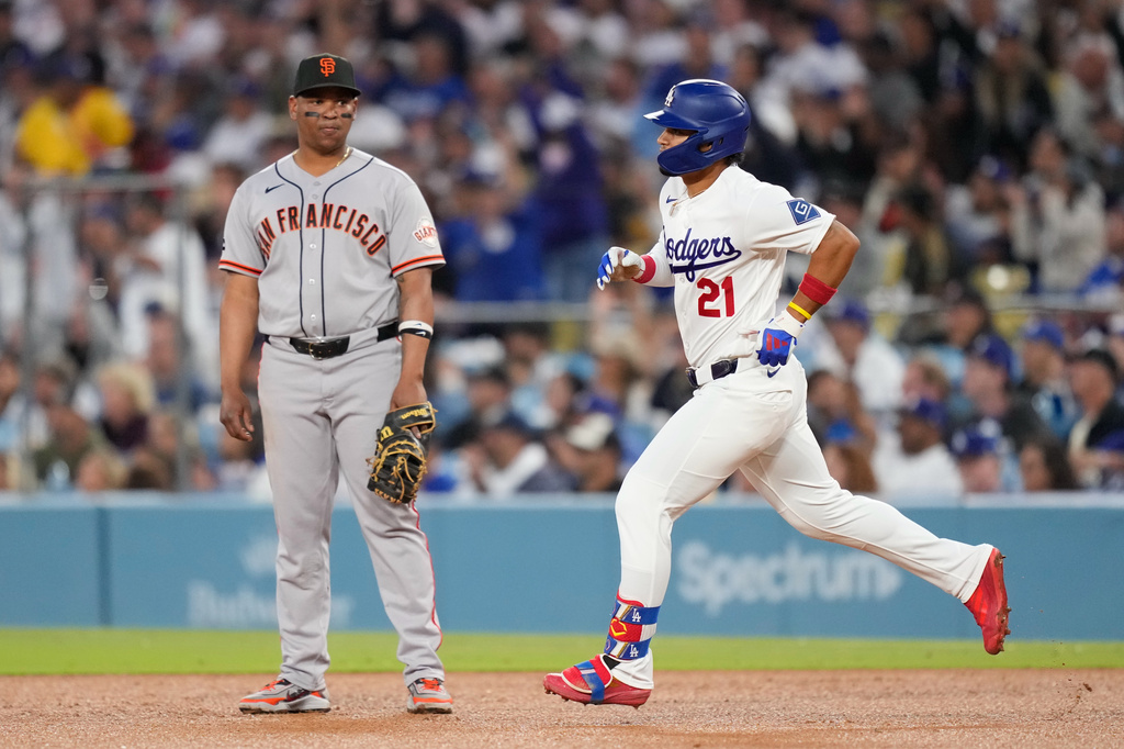 Los Angeles Dodgers' Santiago Espinal, right,heads to second after hitting a solo home run as San Francisco Giants first baseman Rafael Devers watches during the third inning of a baseball game Wednesday, May 13, 2026, in Los Angeles. (AP Photo/Mark J. Terrill)