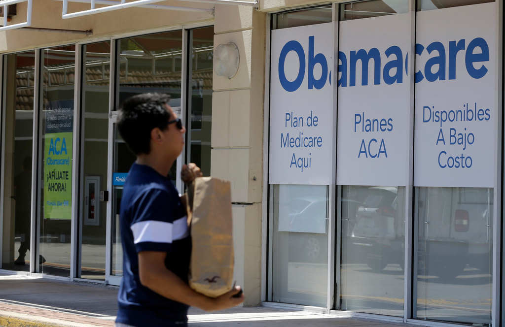 FILE - A man walks by an healthcare insurance office in Hialeah, Fla., July 27, 2017, (AP Photo/Alan Diaz, File)