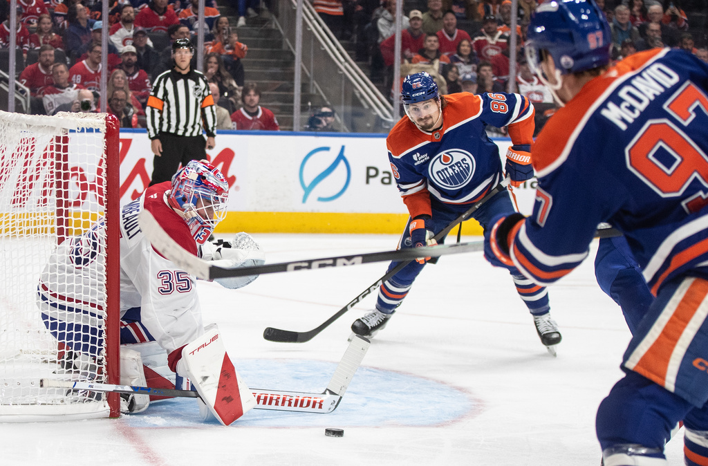 Montreal Canadiens goalie Sam Montembeault (35) makes the save on Edmonton Oilers' Connor McDavid (97) as David Tomasek (86) looks for the rebound during second period NHL action, in Edmonton on Thursday, Oct. 23, 2025.(Jason Franson/The Canadian Press via AP)