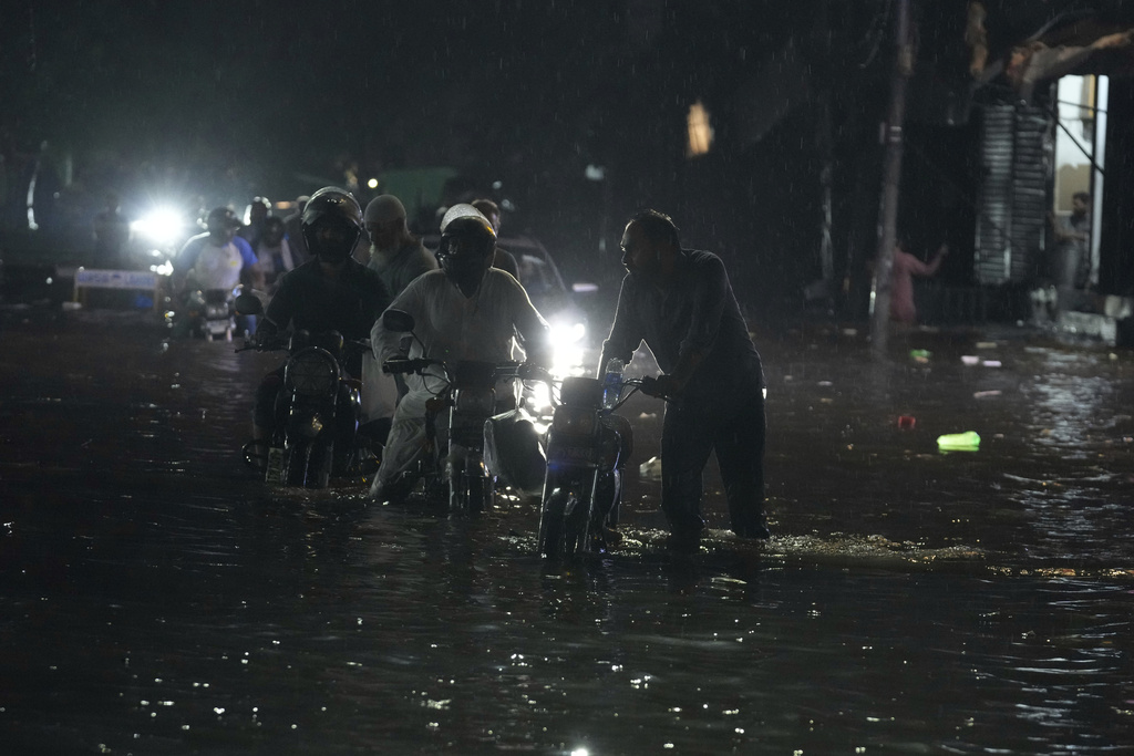 Motorcycles move through a flooded road caused by heavy rain in Lahore, Pakistan, Monday, Sept. 8, 2025. (AP Photo/K.M. Chaudary)