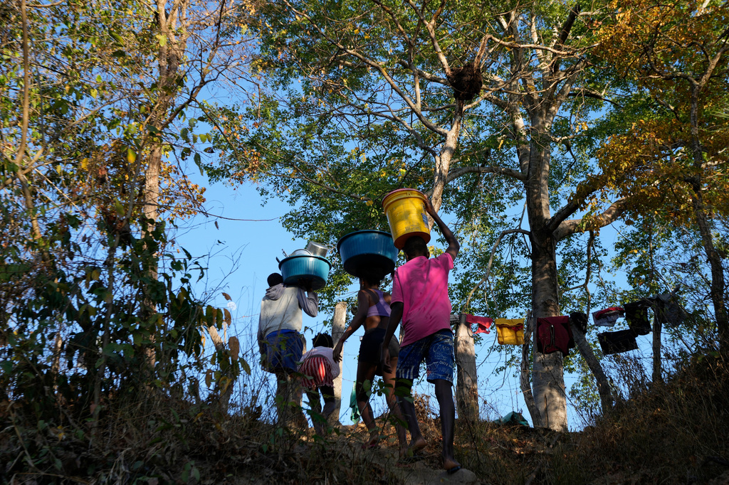 FILE - Children carry water from the Branco River at dawn at the Kalunga quilombo, a Brazilian settlement founded by escaped enslaved Africans, in the rural area of Cavalcante in Goias state, Brazil, Aug. 15, 2022. (AP Photo/Eraldo Peres, File)