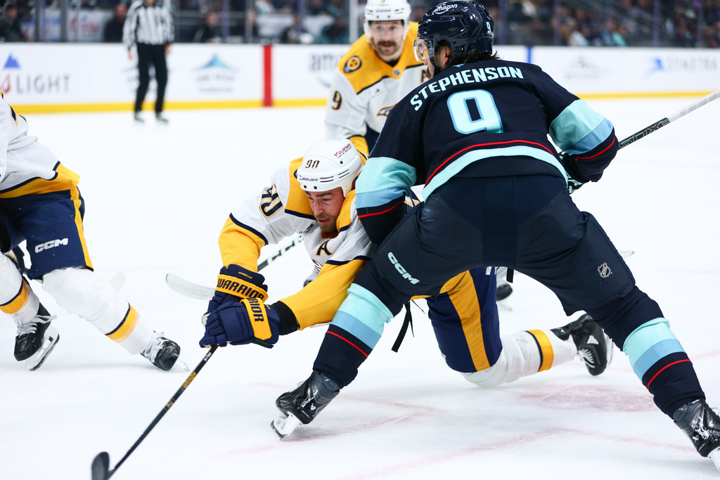 Nashville Predators center Ryan O'Reilly (90) reaches for the puck during a face off in the second period against the Seattle Kraken during an NHL hockey game, Thursday, Jan. 1, 2026, in Seattle. (AP Photo/Kevin Ng)