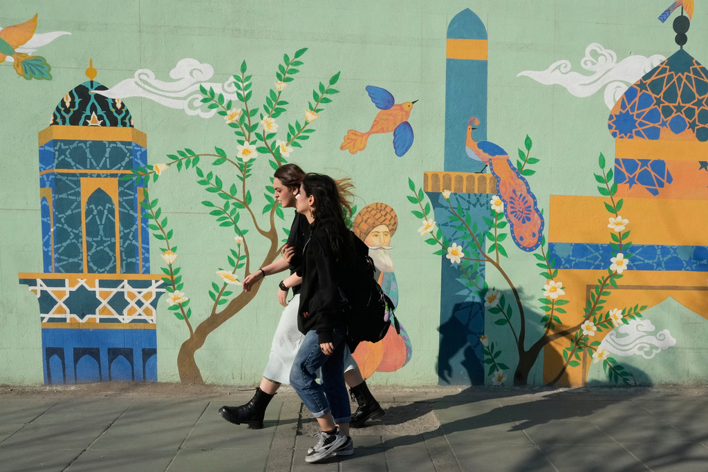 Women walk past an Islamic-themed painting on a wall at Enqelab-e-Eslami, or Islamic Revolution, street in downtown Tehran, Iran, Wednesday, Feb. 25, 2026. (AP Photo/Vahid Salemi)