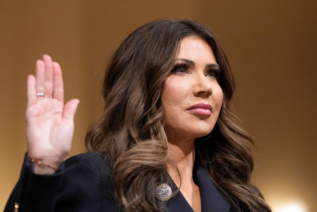 Homeland Security Secretary Kristi Noem raise her arm before the House Committee on Homeland Security on Capitol Hill in Washington, Thursday, Dec. 11, 2025. (AP Photo/Mark Schiefelbein)