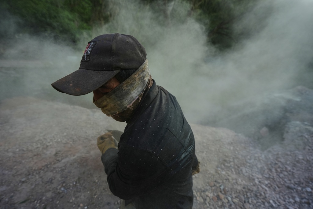 Carlos Martinez discards mercury rocks after baking them in San Joaquin, Mexico, Tuesday, Aug. 19, 2025. (AP Photo/Fernando Llano)