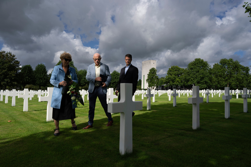 FILE - Eighty years after the liberation of the south of the Netherlands, Scott Taylor, right, Ton Hermes, center, and Maria Kleijnen stand next to the grave of Scott's grandfather Second Lt. Royce Taylor, a bombardier with the 527 Bomb Squadron, at the Netherlands American Cemetery in Margraten, southern Netherlands, Sept. 11, 2024. (AP Photo/Peter Dejong, File)