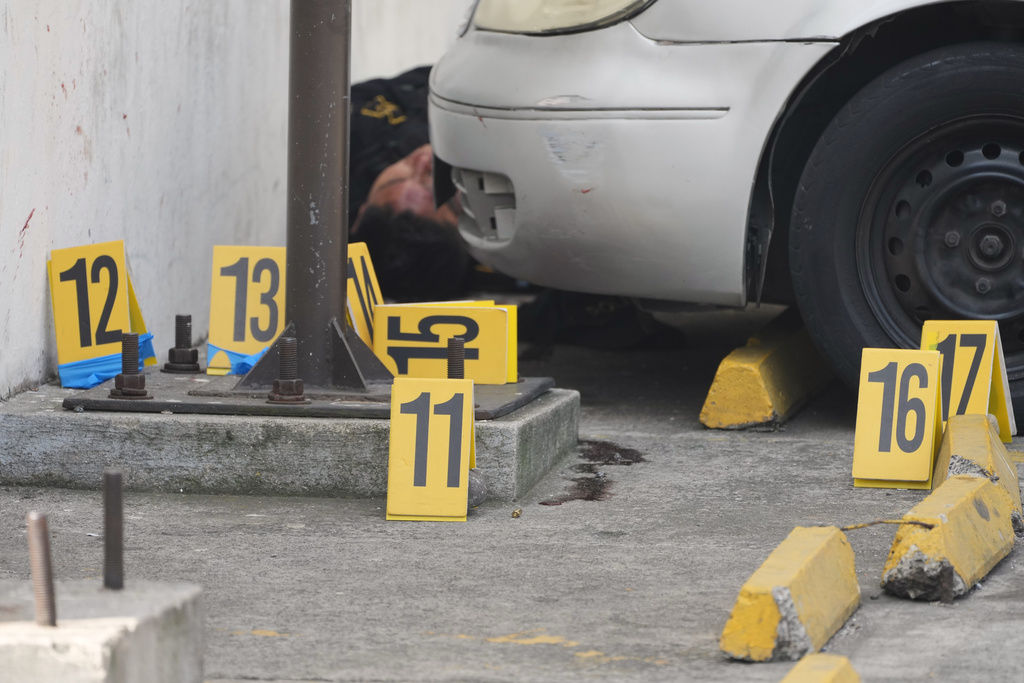 Evidence markers stand at the scene where police officers were killed in attacks reported after security forces retook control of a prison that houses gang leaders, in Villanueva, on the outskirts of Guatemala City, Sunday, Jan. 18, 2026. (AP Photo/Moises Castillo)