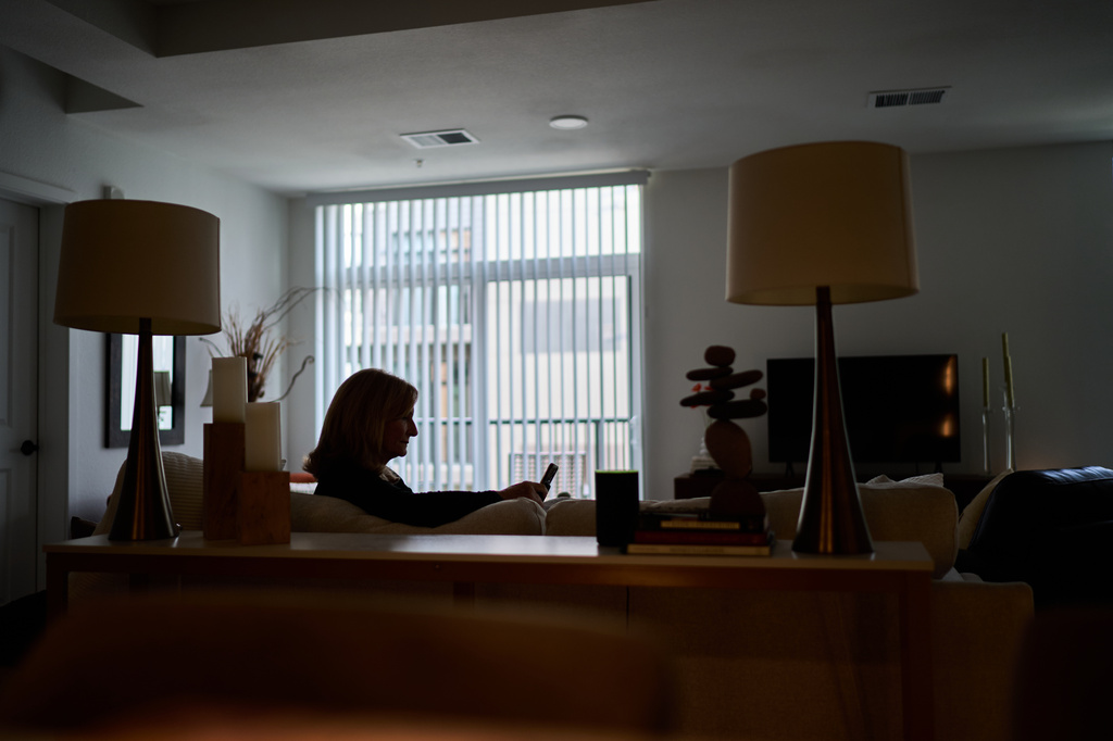 Debra Fox, who had $58,000 stolen from her in a romance scam, looks at her phone, Wednesday, May 13, 2026, at her home in Arvada, Colo. (AP Photo/David Goldman)