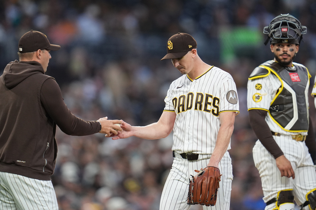 San Diego Padres starting pitcher Walker Buehler, center, hands the ball to manager Craig Stammen as he exits and catcher Luis Campusano looks on, right, during the sixth inning of a baseball game against the Seattle Mariners Thursday, April 16, 2026, in San Diego. (AP Photo/Gregory Bull)