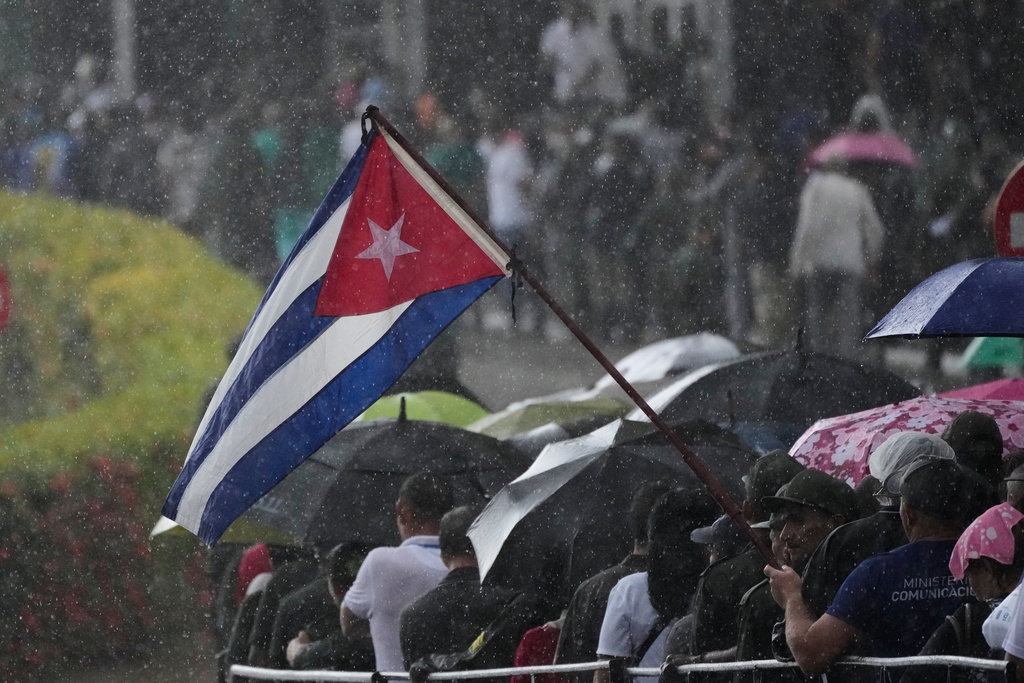 La gente hace fila frente al Ministerio de las Fuerzas Armadas Revolucionarias, donde se exhiben los restos de los oficiales cubanos que murieron durante la operación estadounidense en Venezuela para capturar al expresidente Nicolás Maduro, mientras llueve ligeramente en La Habana, Cuba, el jueves 15 de enero de 2026. (Foto AP/Ramón Espinosa)