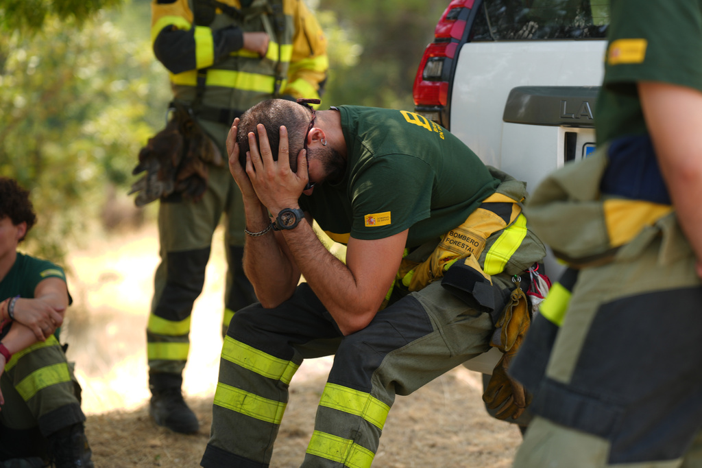 Aesir Diaz, 31, a technician with Spain's Forest Fire Reinforcement Brigades (BRIF), center, sits next to teammates during a break from battling a wildfire in Sotillo de Adrada, Ávila province, Spain, as the fire continues to spread, Tuesday, July 28, 2026. (AP Photo/Manu Fernandez)