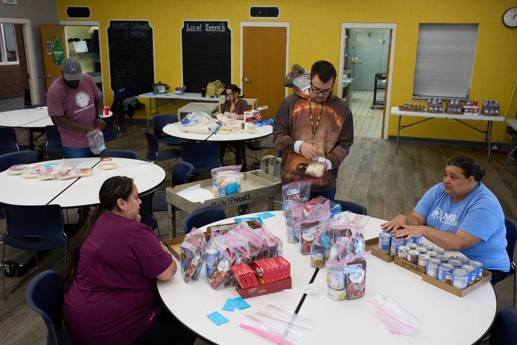 Faculty at Nueta Hidatsa Sahnish College prepare bagged meals for a food bank for students Thursday, Oct. 30, 2025, in New Town, N.D. (AP Photo/John Locher)
