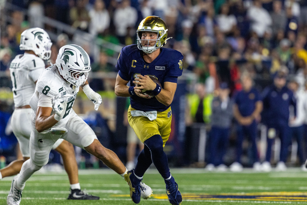 Notre Dame quarterback CJ Carr (13) avoids a sack and scrambles with the ball during the first half of a college football game against Michigan State, Saturday, Sept. 19, 2026, in South Bend, Ind. (AP Photo/Paul Barnick)
