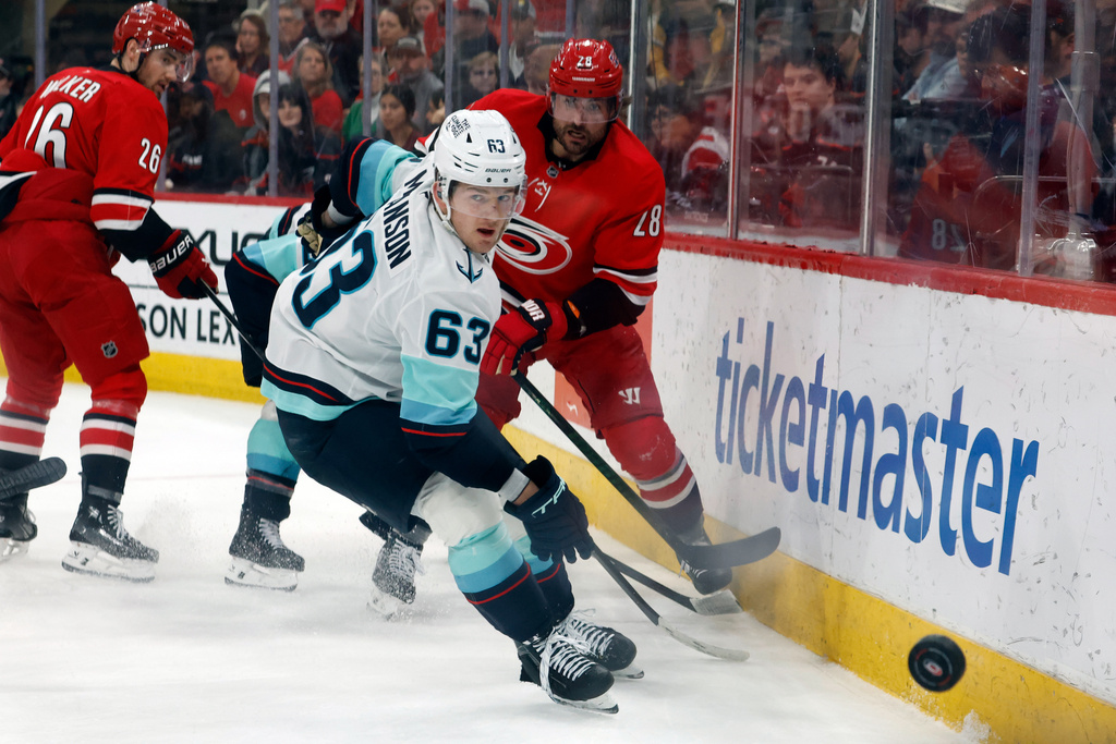 Carolina Hurricanes' William Carrier (28) clears the puck past Seattle Kraken's Jacob Melanson (63) during the first period of an NHL hockey game in Raleigh, N.C., Saturday, Jan. 10, 2026. (AP Photo/Karl DeBlaker)