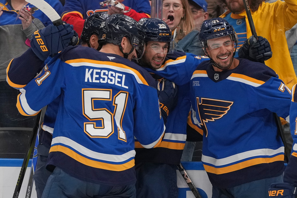 St. Louis Blues' Jordan Kyrou, center, is congratulated by Matthew Kessel (51) and Mathieu Joseph (71) after scoring during the second period of an NHL hockey game against the Dallas Stars Saturday, Oct. 18, 2025, in St. Louis. (AP Photo/Jeff Roberson)