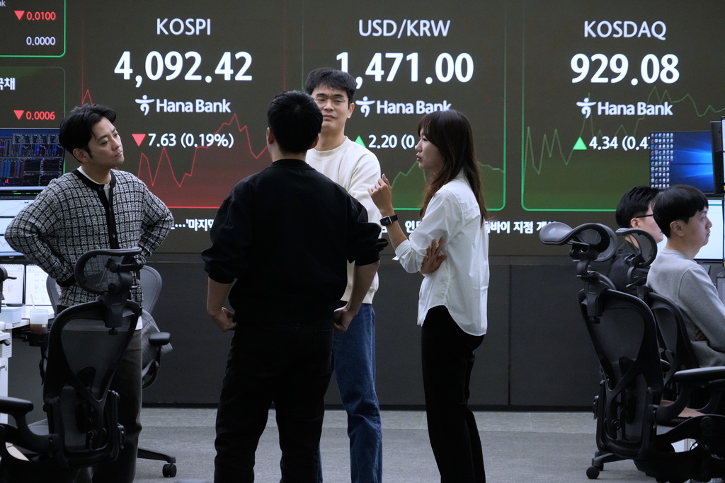 Currency traders work near a screen showing the Korea Composite Stock Price Index (KOSPI), top left, and the foreign exchange rate between U.S. dollar and South Korean won, top center, at the foreign exchange dealing room of the Hana Bank headquarters in Seoul, South Korea, Monday, Dec. 8, 2025. (AP Photo/Ahn Young-joon)