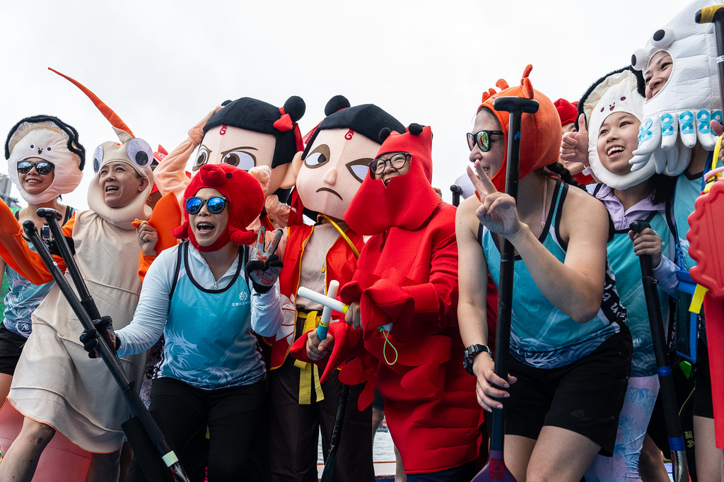 Competitors in costumes pose for photographs before the Aberdeen Dragon Boat Race to celebrate the Dragon Boat Festival in Hong Kong, Friday, June 19, 2026. (AP Photo/Chan Long Hei)