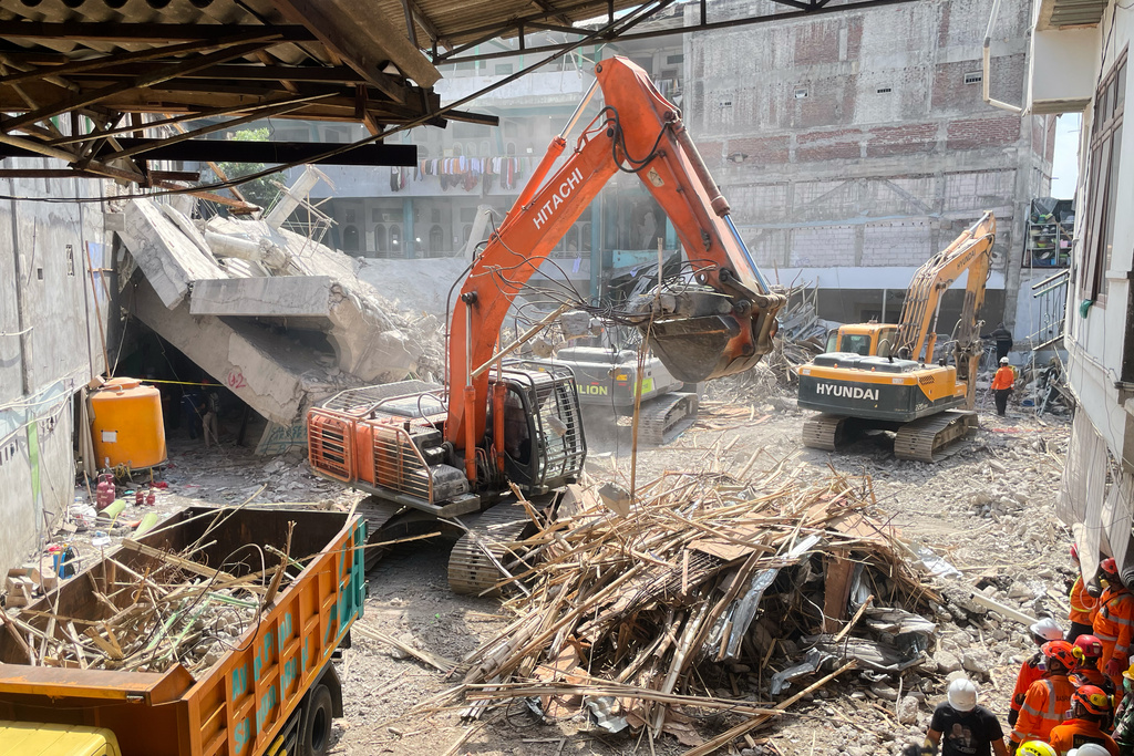Rescuers use heavy machines to clear the rubble during the search for victims at a building that collapsed at an Islamic boarding school in Sidoarjo, East Java, Indonesia, Sunday, Oct. 5, 2025. (AP Photo/Trisnadi)