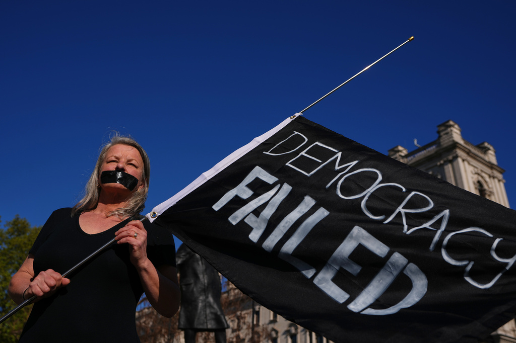 Campaigner Louise Shackleton holds a banner outside parliament in London as a proposed law to legalise assisted dying in England and Wales will run out of time on Friday, more than a year after MPs first voted in favour of it, Friday, April 24, 2026. (AP Photo/Kirsty Wigglesworth)