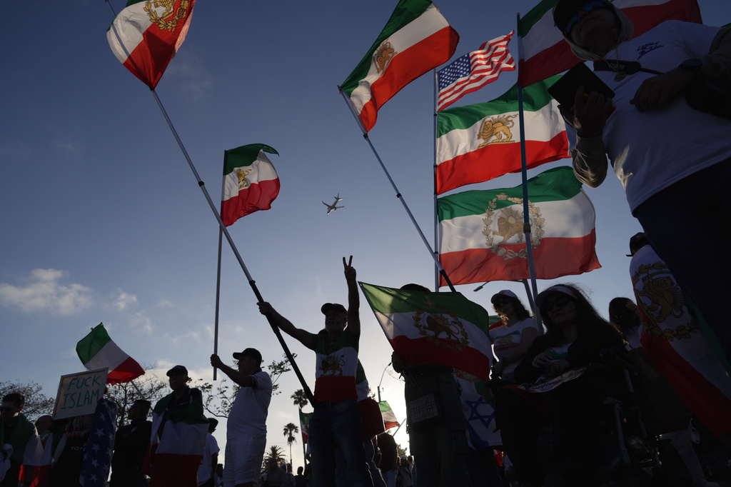 People wave pre-revolutionary Iranian flags during a protest outside Los Angeles Stadium before the World Cup Group G soccer match between Iran and New Zealand in Inglewood, Calif., near Los Angeles, Monday, June 15, 2026. (AP Photo/Ty ONeil)