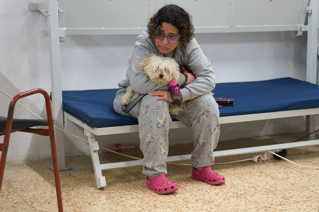Nofar Eliash grasps her dog as she takes shelter while air raid sirens warn of incoming Iranian and Hezbollah missile strikes in Kiryat Shmona, northern Israel, Monday, March 16, 2026. (AP Photo/Ariel Schalit)