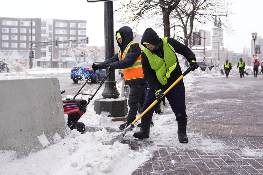 Workers clear snow off the ground Sunday, March 15, 2026, in St. Paul, Minn. (AP Photo/Abbie Parr)