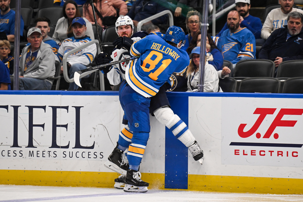 St. Louis Blues' Dylan Holloway (81) checks Winnipeg Jets' Dylan Samberg, center left, during the third period of an NHL hockey game Thursday, April 9, 2026, in St. Louis. (AP Photo/Connor Hamilton)